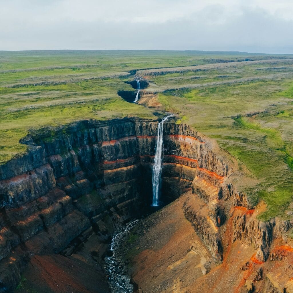 an aerial view of a waterfall in a canyon