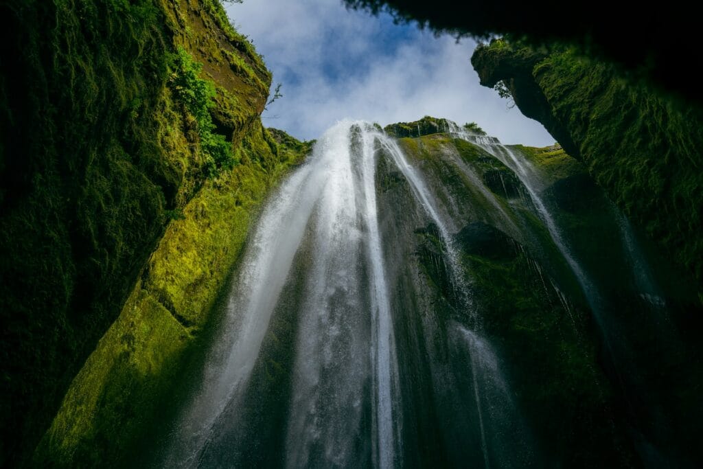 A waterfall is seen through a hole in the ground
