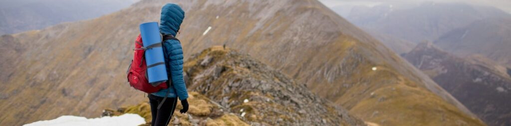 person at peak of mountain carrying red backpack