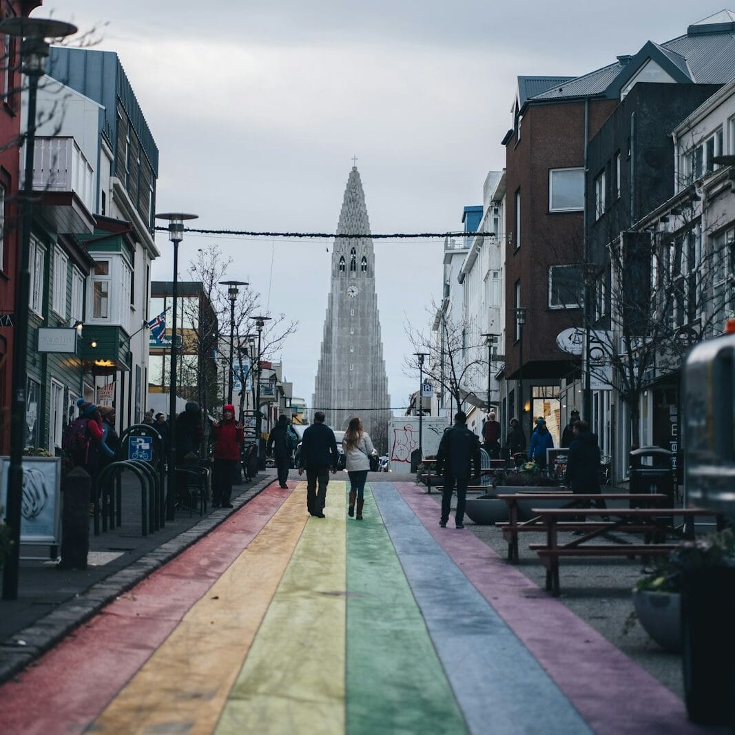 a rainbow painted street with people walking down it