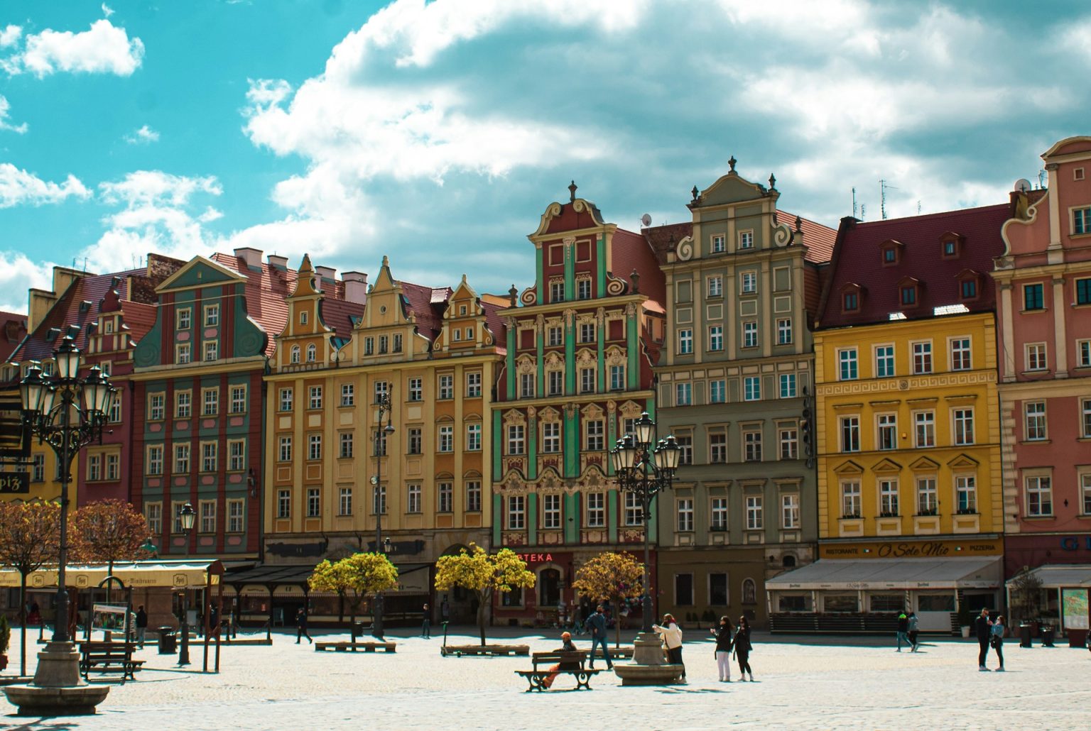 Wrocław, Polska, people walking on street near brown concrete building during daytime