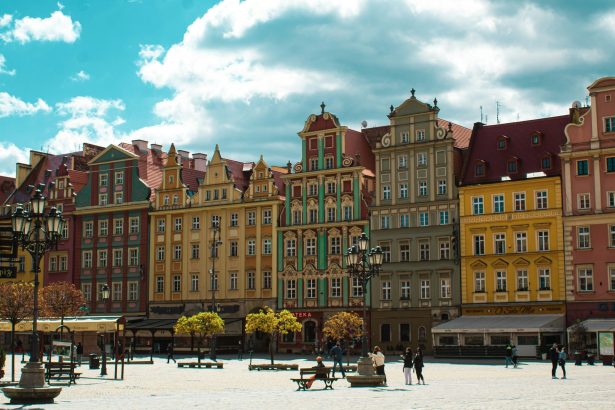 Wrocław, Polska, people walking on street near brown concrete building during daytime
