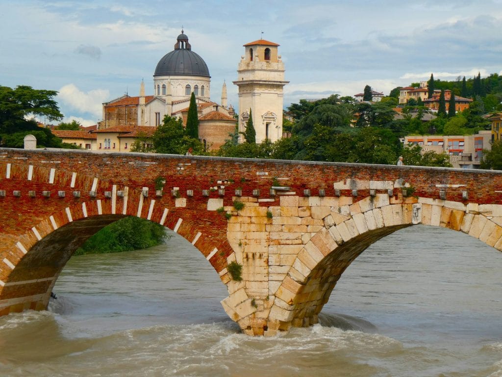 Ponte Pietra , A stone bridge over a river with a church in the background