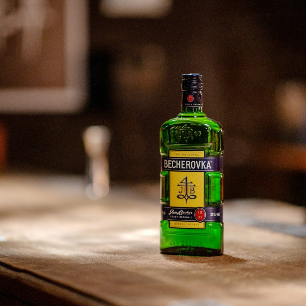 Becherovka a bottle of alcohol sitting on top of a wooden table