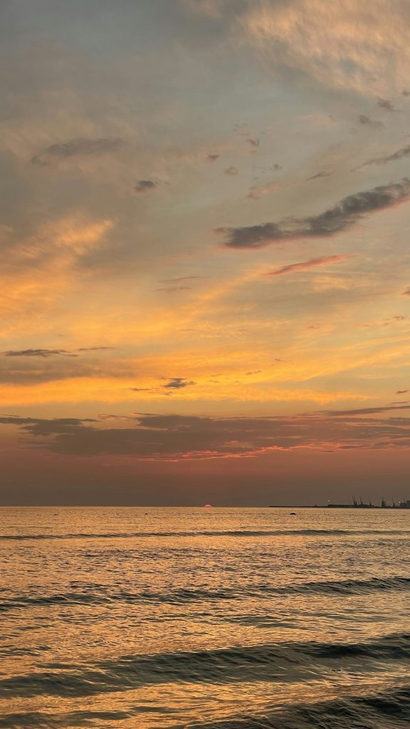 A sunset over a body of water with a boat in the distance