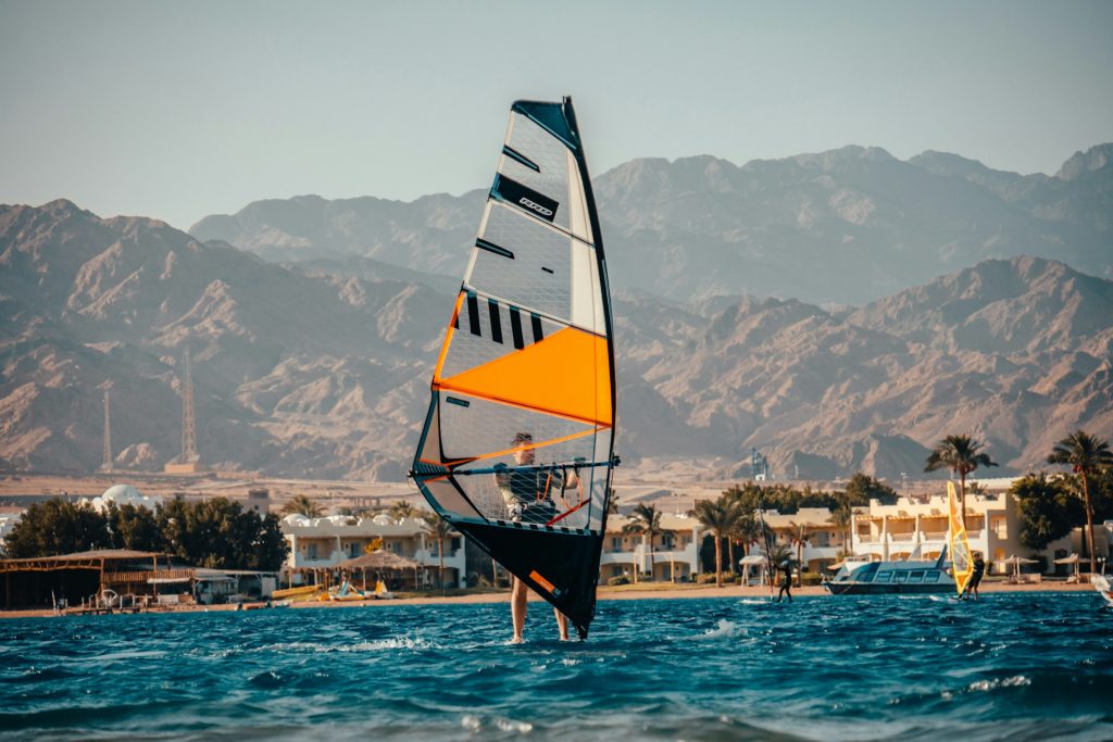 red and white sail boat on water near city buildings during daytime
