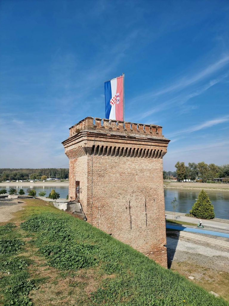 A historic brick tower with a Croatian flag in Osijek, Croatia.