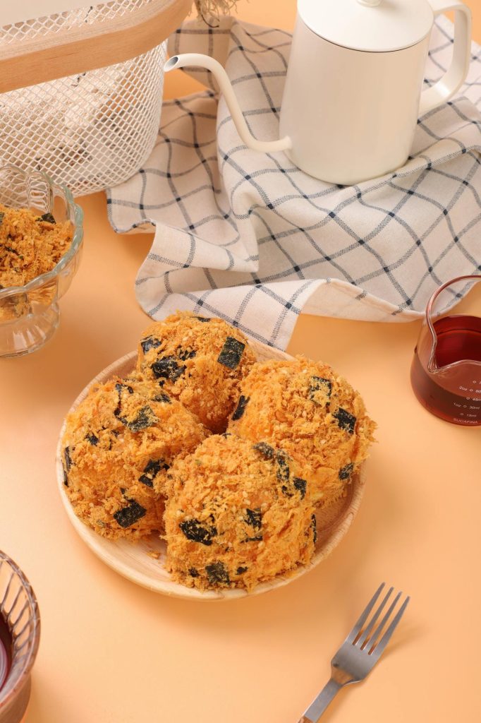 Delicious rice balls with seaweed served on a plate with a cup of sauce and tea setup.