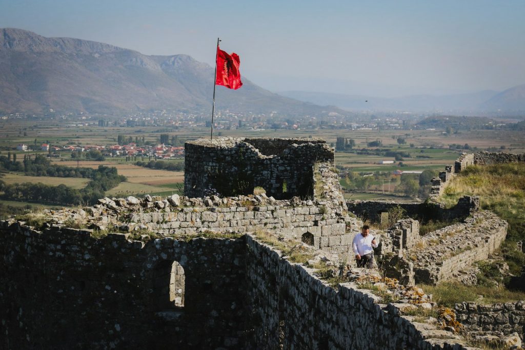 a man sitting on a stone wall next to a flag