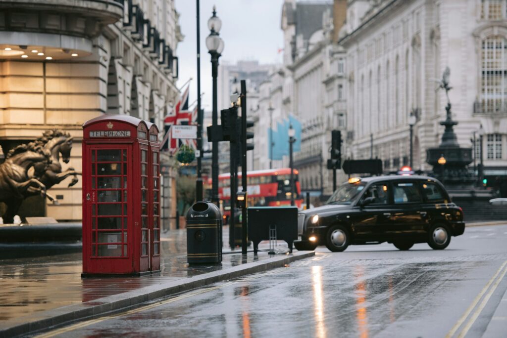 a car driving down a street next to a red phone booth